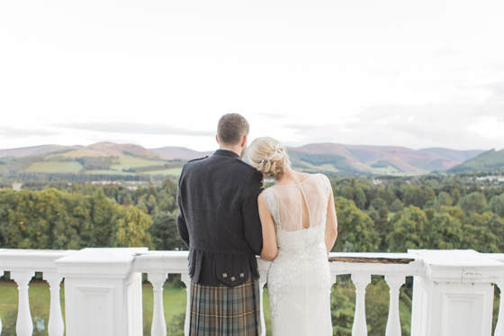 Bride rests her head on grooms shoulder as they look at the view from Peebles Hydro Hotel balcony